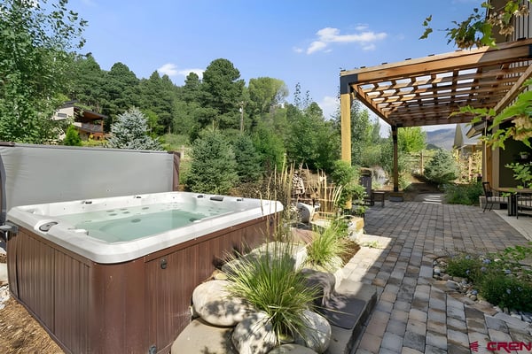 Hot tub on patio with pergola, paver deck, and forested mountain views