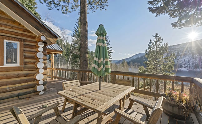 Log cabin deck with outdoor dining table and mountain views