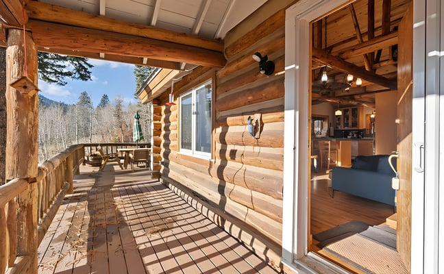 Log cabin wraparound deck with view into the living area